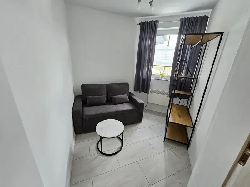 Dasselbe Zimmer nach der Renovierung mit weißen Wänden und großformatigen Bodenfliesen